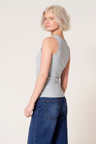 Blauwe singlet van Clouds of Fashion, met een ribgebreide textuur, gedragen met wijde jeans.
