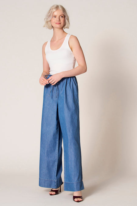 Witte singlet van Clouds of Fashion, gedragen met wijde, blauwe denim broek en bordeauxrode muiltjes.