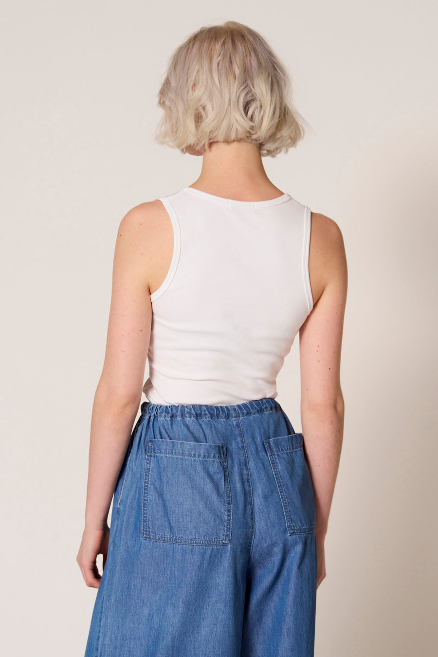 Witte singlet van Clouds of Fashion, gezien van achteren, gecombineerd met een blauwe broek.
