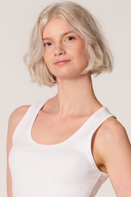 Witte singlet van Clouds of Fashion, gedragen door een vrouw met een bobkapsel op een effen achtergrond.
