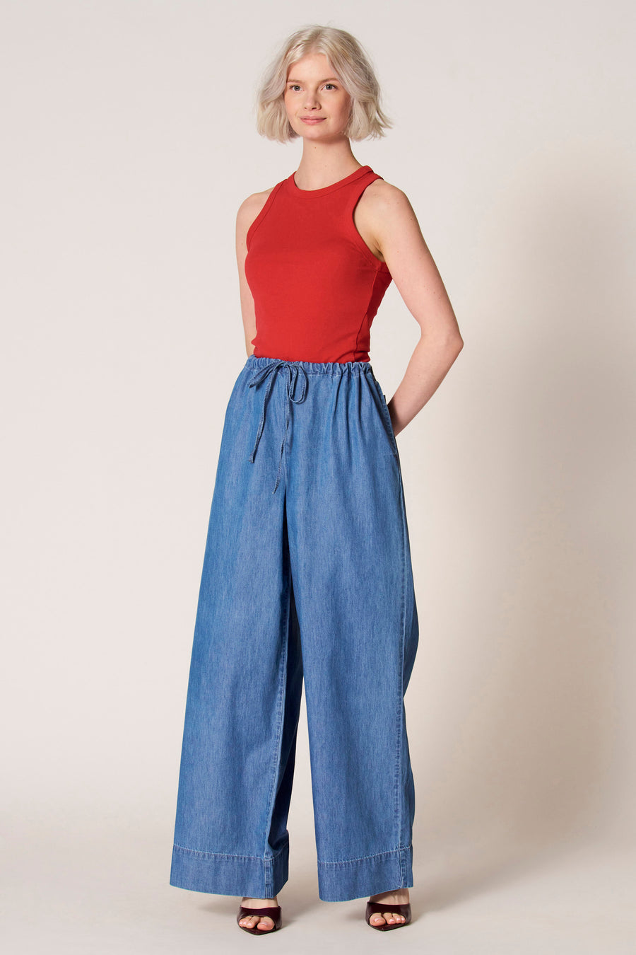 Rode singlet van Clouds of Fashion, gedragen met wijde blauwe broek en sandalen met hak.