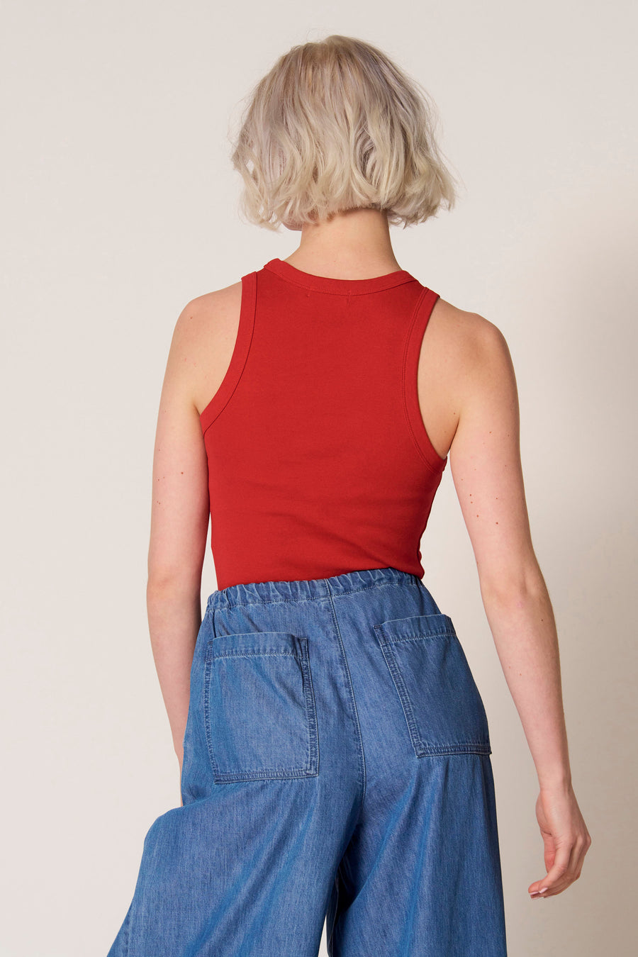 Rode singlet van Clouds of Fashion, met een ronde hals en zichtbare jeans broek met zakken.
