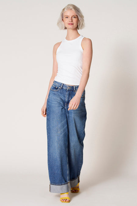 Witte singlet van Clouds of Fashion, gedragen met een jeans met wijde pijpen en gele hakken.