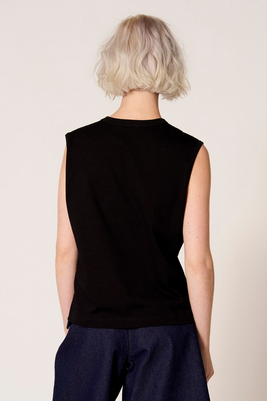 Zwarte singlet van Clouds of Fashion, gezien van achteren, gecombineerd met een donkerblauwe broek.
