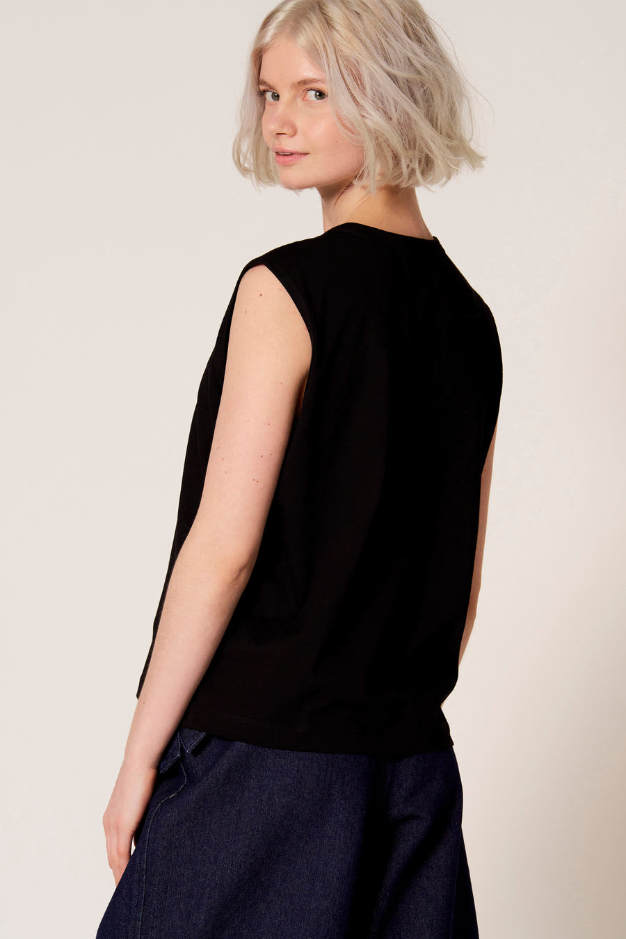 Zwarte singlet van Clouds of Fashion, met een casual pasvorm en gecombineerd met een donkerblauwe broek.
