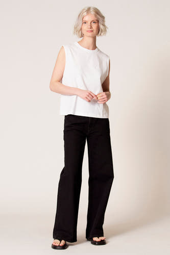 Débardeur blanc de Clouds of Fashion, au design simple, porté avec un pantalon noir.