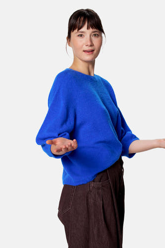 Blauwe korte mouwen pull van Clouds of Fashion, gebreid met losse pasvorm, gedragen met donkere broek, zijprofiel.