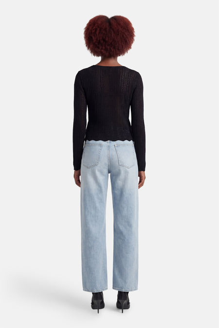 Zwart shirt met lange mouwen van HAILYS, met een open gebreid patroon en een geschulpte zoom, gedragen met wijde jeans en hakken.
