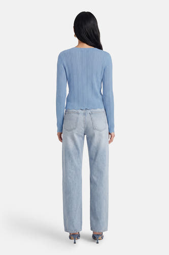 Blauw T-shirt met lange mouwen van HAILYS, gezien van achteren, gecombineerd met een lichtblauwe jeans en hakken.