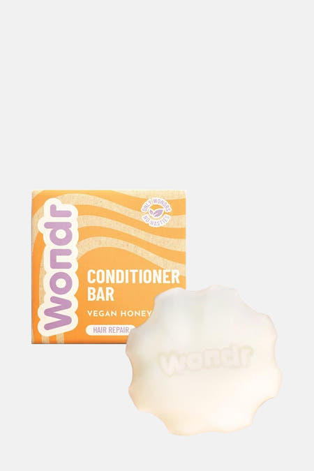 Vegan conditioner bar van Wondr Care, met de merknaam subtiel op de zeep gedrukt, naast de verpakking met honingraatpatroon.