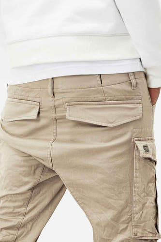 Jean cargo beige de G-Star RAW, avec des poches derrière et sur la cuisse, et un pull blanc partiellement visible.
