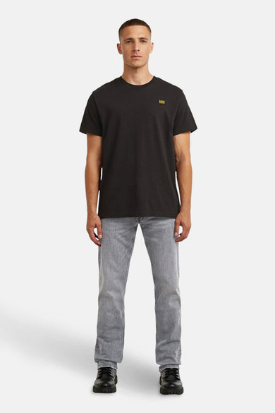 Grijze straight jeans van G-Star RAW, gecombineerd met een zwart T-shirt en zwarte schoenen.