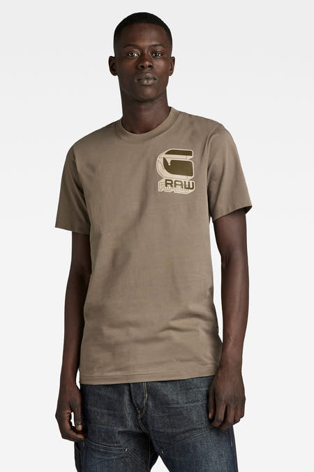 Bruin T-shirt van G-Star RAW, met een logo op de borst en gedragen met een donkere jeans.
