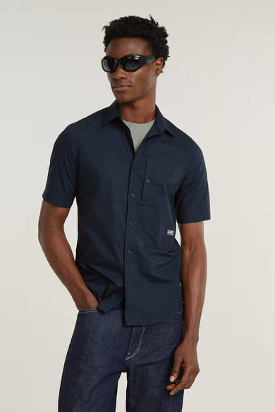 Zwart overhemd met korte mouwen van G-Star RAW, met borstzak en gedragen met een grijs T-shirt en donkere jeans.
