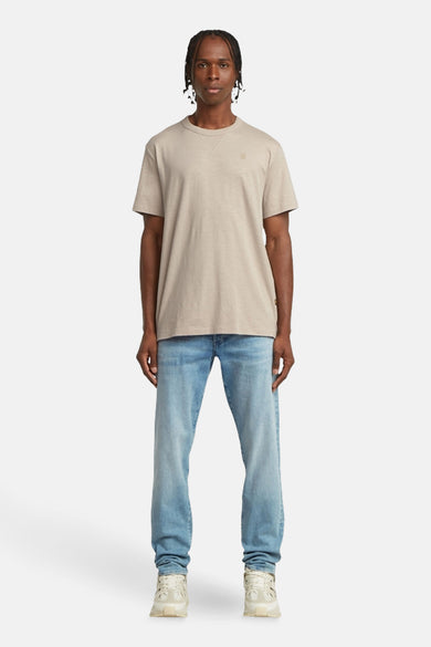 Ecru T-shirt met korte mouwen van G-Star RAW, met een ronde hals en gedragen met blauwe jeans en witte sneakers.