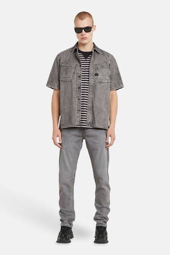 Grijs jeanshemd van G-Star RAW, gedragen over een gestreept shirt, met bijpassende jeans en zwarte sneakers.