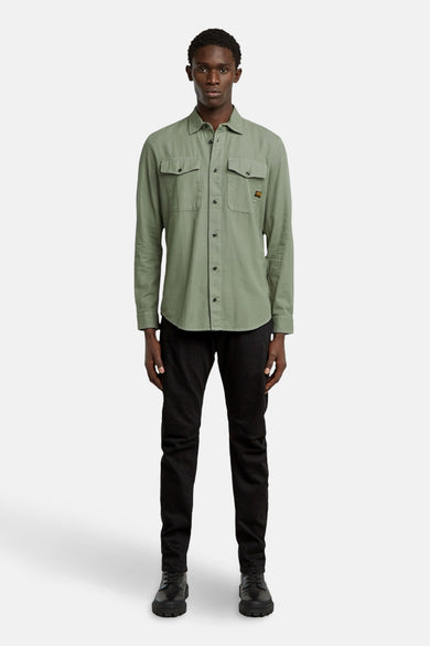 Groen hemd met lange mouwen van G-Star RAW, met twee borstzakken en zwarte broek en schoenen.