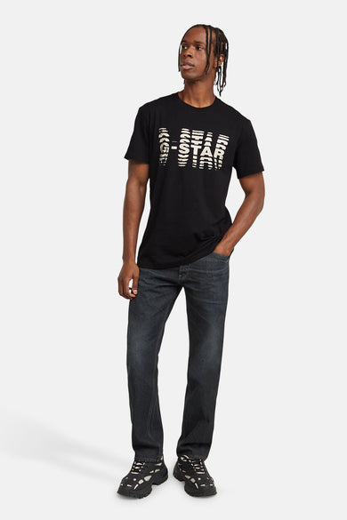 Zwart T-shirt met korte mouwen van G-Star RAW, met een witte 'G-STAR' tekstprint op de voorkant, gedragen met jeans en sneakers.
