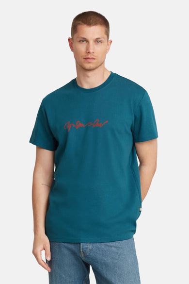 Blauw T-shirt met korte mouwen van G-Star RAW, met rode merknaam op de borst en model met jeans.