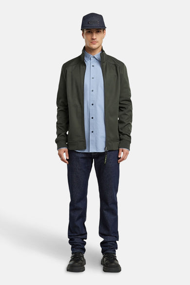 Chemise bleue à manches longues de G-Star RAW, portée avec une veste verte et des jeans bleu marine.