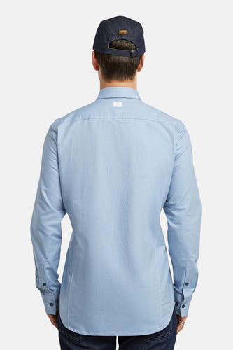 Blauw overhemd met lange mouwen van G-Star RAW, gezien van achteren, met een donkerblauwe pet.