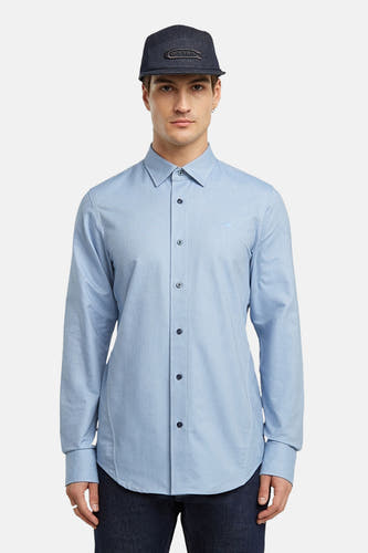 Blauw overhemd met lange mouwen van G-Star RAW, gedragen met een donkerblauwe pet.