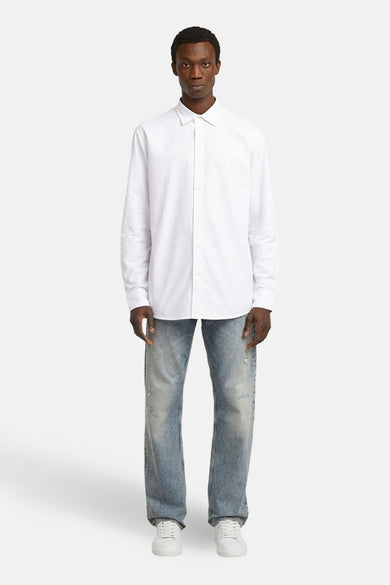 Wit overhemd met lange mouwen van G-Star RAW, gedragen met jeans en witte sneakers.