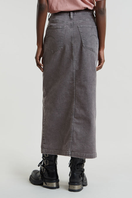 Lange mid grey denim rok van G-Star RAW met zichtbare stiksels en achterzakken, gedragen met een roze top en zwarte laarzen, achterkant.