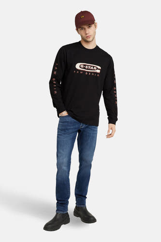Jeans slim fit en denim bleu de G-Star RAW, combinés avec un t-shirt noir à manches longues et une casquette.