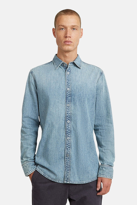 Een man met een blauw denim overhemd.
