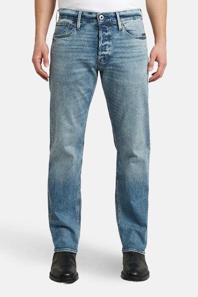 Tapered jeans van midblauw denim van G-Star RAW, met knoopsluiting en zwarte schoenen.
