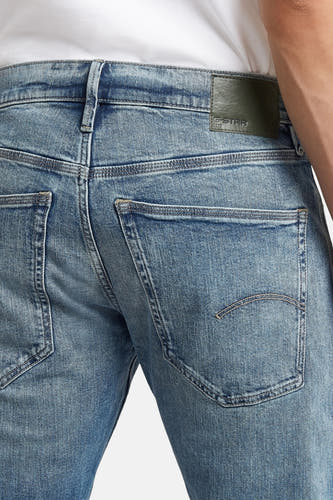Jean fuselé en denim bleu de G-Star RAW, avec poches arrière et une étiquette de marque.