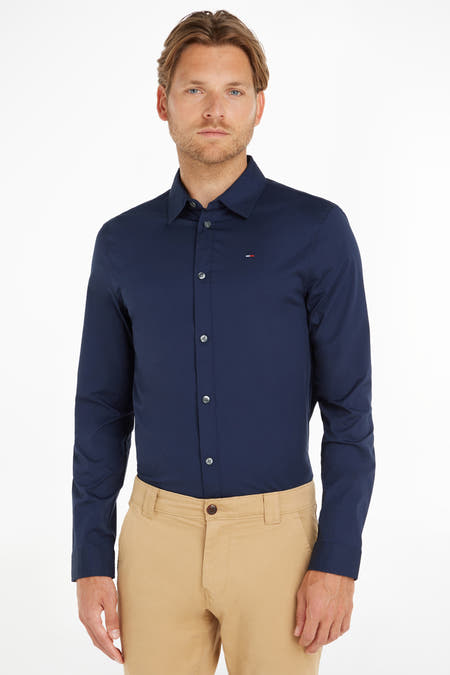 Blauw overhemd met lange mouwen van TOMMY JEANS, met knoopsluiting, gedragen met een kaki broek.
