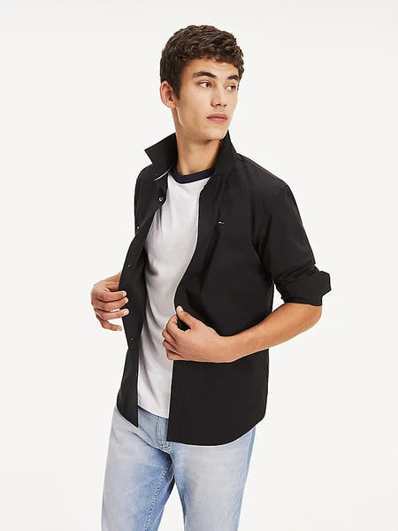 Zwart overhemd met lange mouwen van TOMMY JEANS, gedragen over een wit T-shirt en een lichte jeans.
