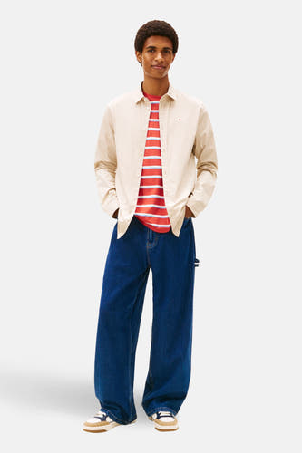 Beige overhemd met lange mouwen van TOMMY JEANS, gedragen over een gestreept T-shirt en wijde jeans.
