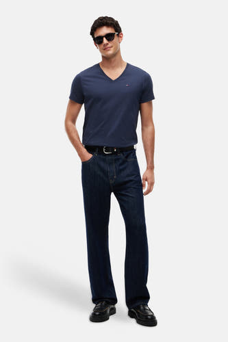 Blauwe V-hals T-shirt van TOMMY JEANS, gedragen met donkerblauwe jeans en zwarte loafers, front view.