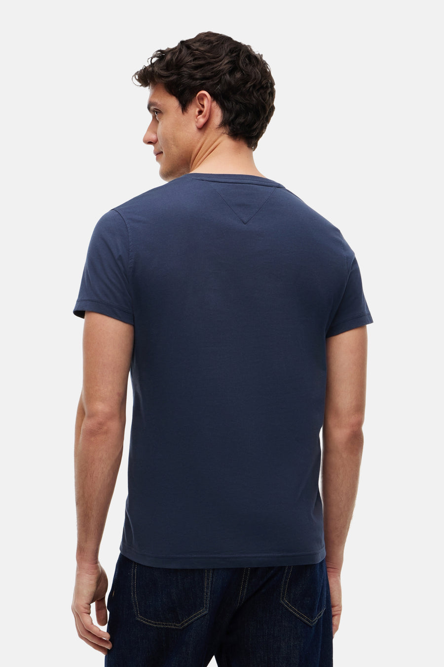 Blauwe korte mouw T-shirt van TOMMY JEANS, achterzijde, gladde stof, model in donkerblauwe jeans