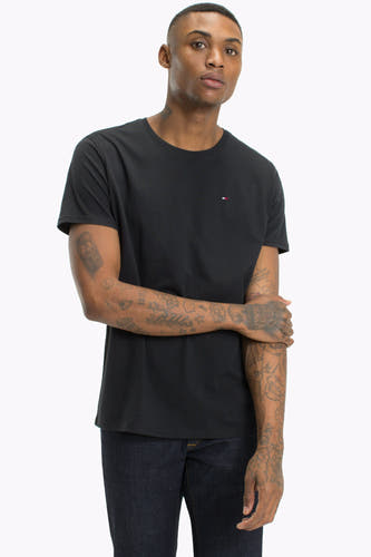 Zwart T-shirt van TOMMY JEANS, met korte mouwen en een klein logo op de borst, gedragen met donkerblauwe jeans.
