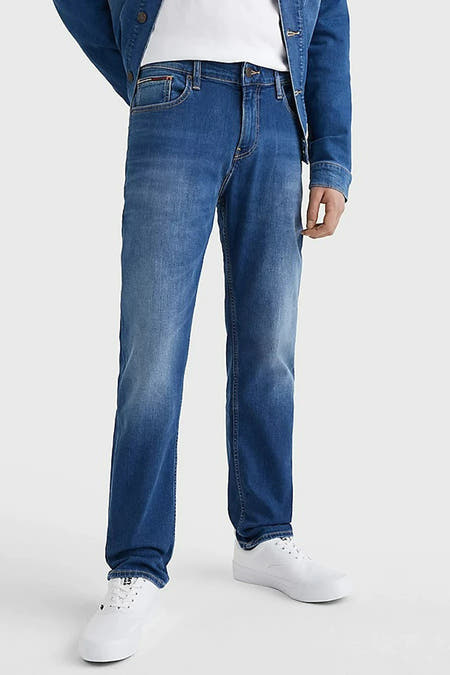 Blauwe straight jeans van TOMMY JEANS, gecombineerd met een spijkerjack en witte schoenen.

