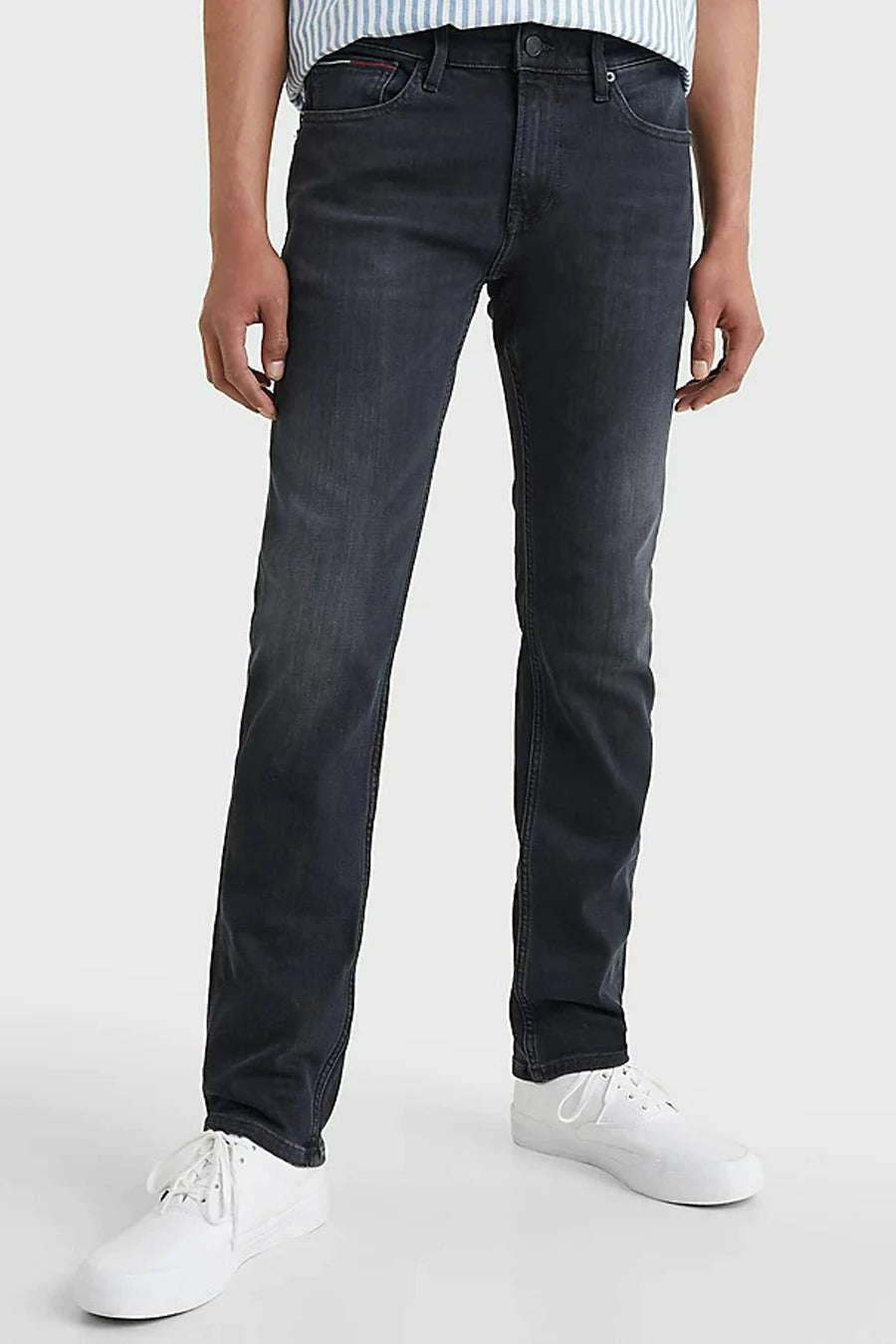 Donkergrijze slim fit jeans van TOMMY JEANS, met een subtiele wassing en witte sneakers.
