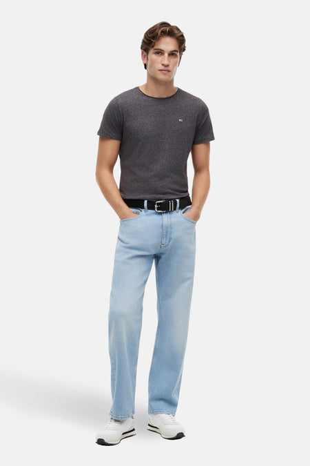 Zwart T-shirt van TOMMY JEANS, met korte mouwen, gecombineerd met lichtblauwe jeans en witte sneakers.