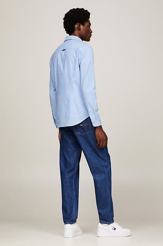 Blauw overhemd met lange mouwen van TOMMY JEANS, gezien van achteren, gecombineerd met jeans en witte sneakers.
