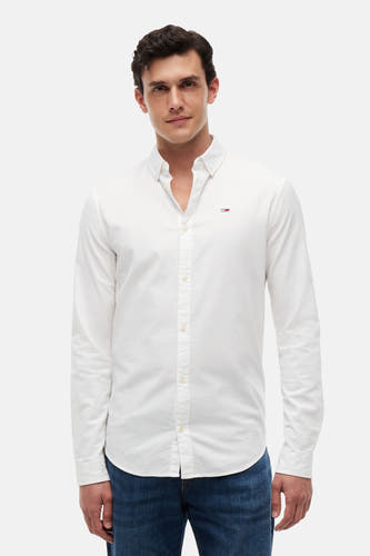 Wit overhemd met lange mouwen van TOMMY JEANS, met klein vlaglogo op de borst, knoopkraag, gedragen met blauwe jeans.