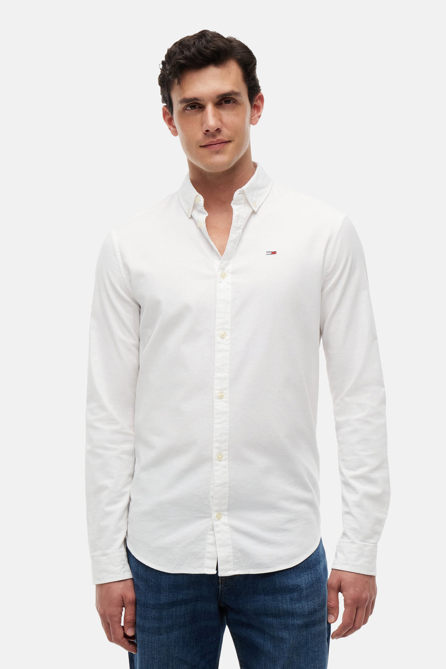 Wit overhemd met lange mouwen van TOMMY JEANS, met klein vlaglogo op de borst, knoopkraag, gedragen met blauwe jeans.