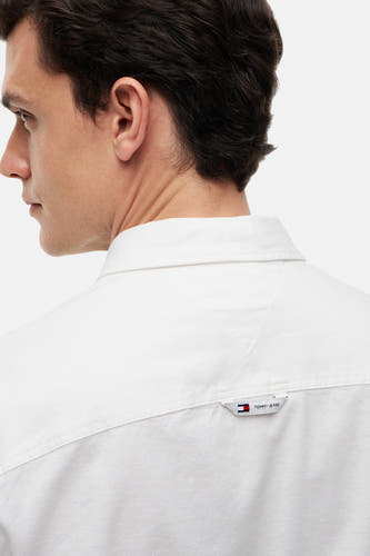Wit hemd met lange mouwen van TOMMY JEANS, van achteren gezien met klein merklabel op de rug.