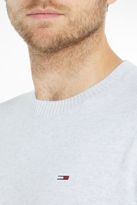 Grijze ronde hals trui van TOMMY JEANS met klein logo op borst, close-up van model