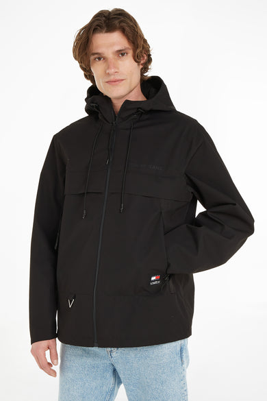 Zwarte korte jas met capuchon van TOMMY JEANS, voorzien van rits, zakken en logo-patch, front view op model in lichtblauwe jeans