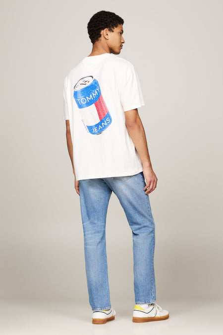 Ecru T-shirt met korte mouwen van TOMMY JEANS, met een blikjesprint op de rug, gecombineerd met blauwe jeans en witte sneakers.
