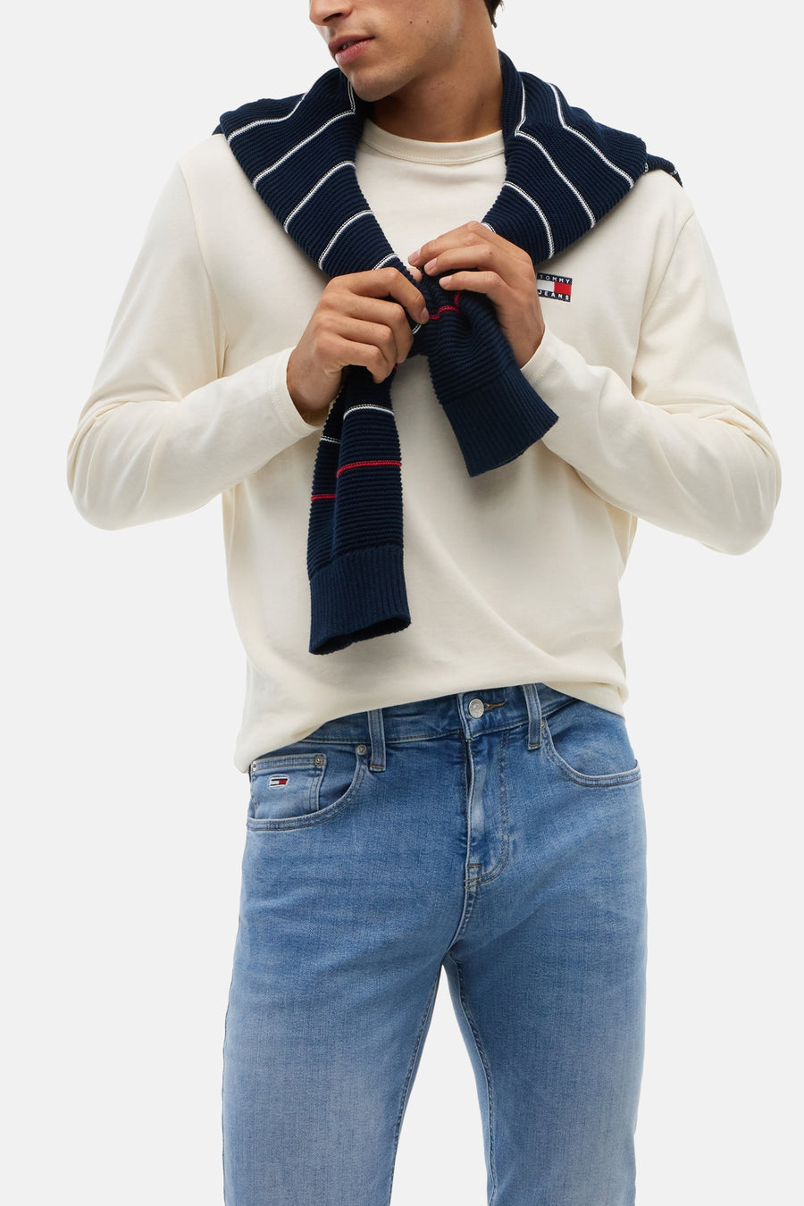 Jean slim bleu moyen de TOMMY JEANS, avec un léger effet délavé, poches visibles, porté par un mannequin en chemise blanche avec une écharpe.