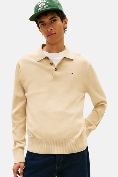 Beige trui van TOMMY JEANS met lange mouwen en een polokraag, gedragen met een wit T-shirt en een groene pet.
